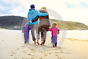 Happy young family is walking on sandy beach and ocean